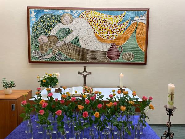 Quelle: Friedensgemeinde Baden-Baden Bild: Kapelle mit Altar im Haus Elia, im Hintergrund Mosaik Elia wird vom Engel versorgt. Im Vordergrund Rosen vom Gedenkgottesdienst für Verstorbene.