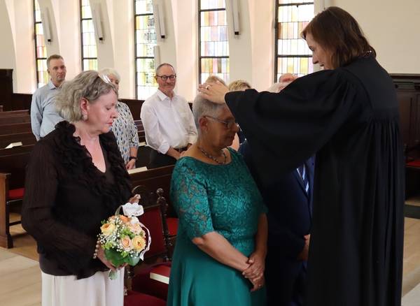 Bild: Hochzeitspaar wird von Pfarrerin gesegnet in der Friedenskirche.